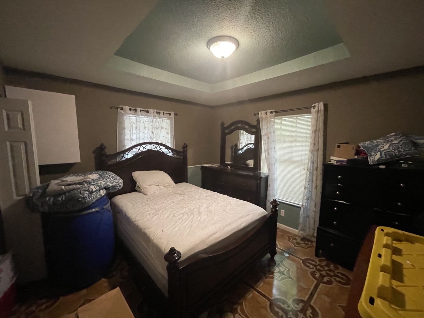 Cluttered tenant-occupied bedroom with dark furniture before sale
